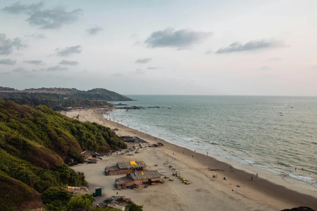 High-angle view of a sandy Goa beach with tropical greenery, rustic beach shacks