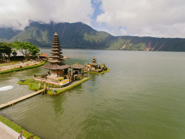 Pura Ulun Danu Beratan temple on Lake Beratan in Bali, with mountains and cloudy skies in the background.