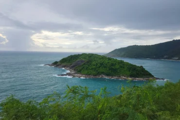 A lush green island surrounded by turquoise ocean waters in Phuket, Thailand.
