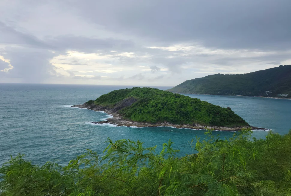 A lush green island surrounded by turquoise ocean waters in Phuket, Thailand.
