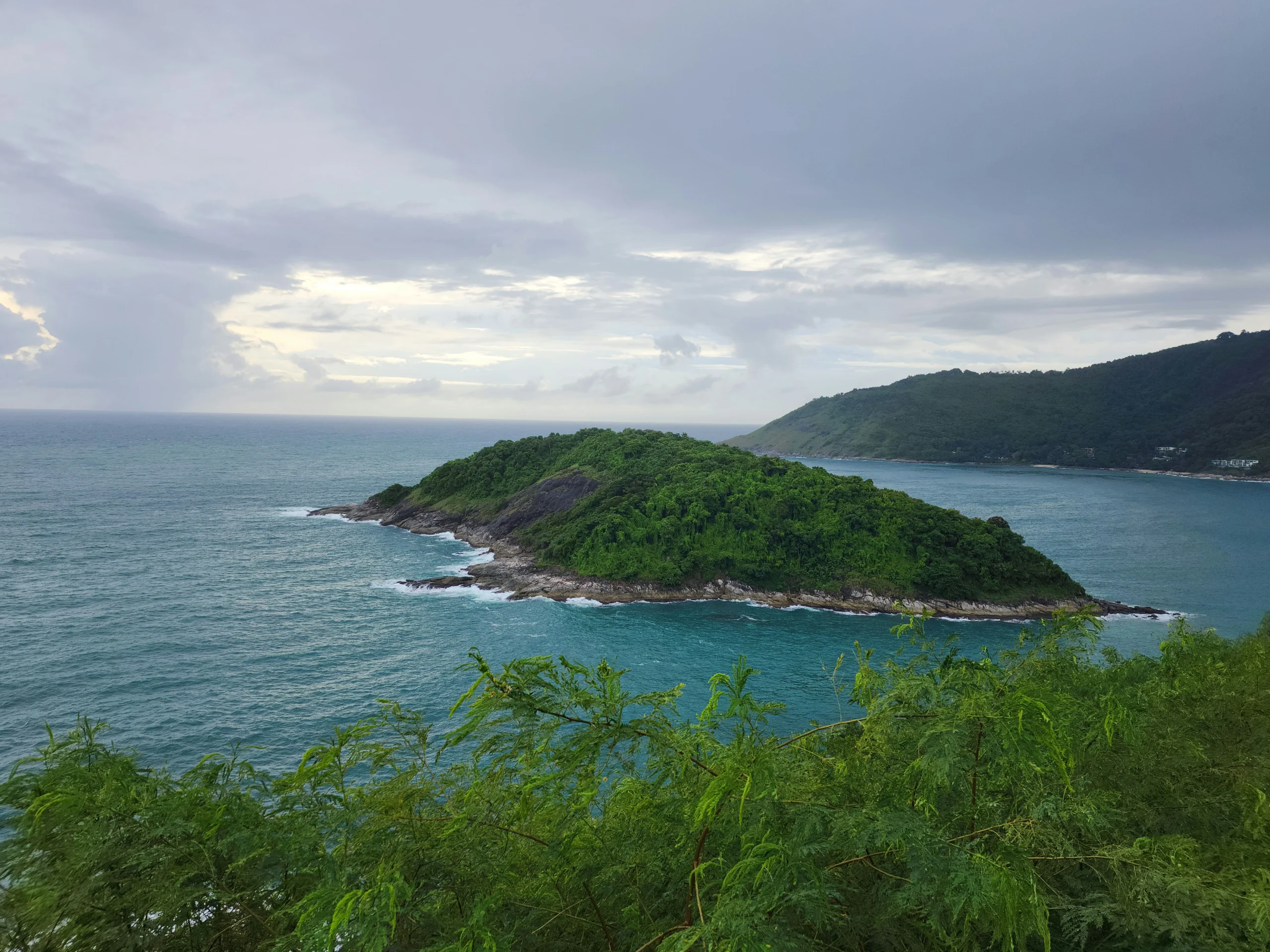 A lush green island surrounded by turquoise ocean waters in Phuket, Thailand.