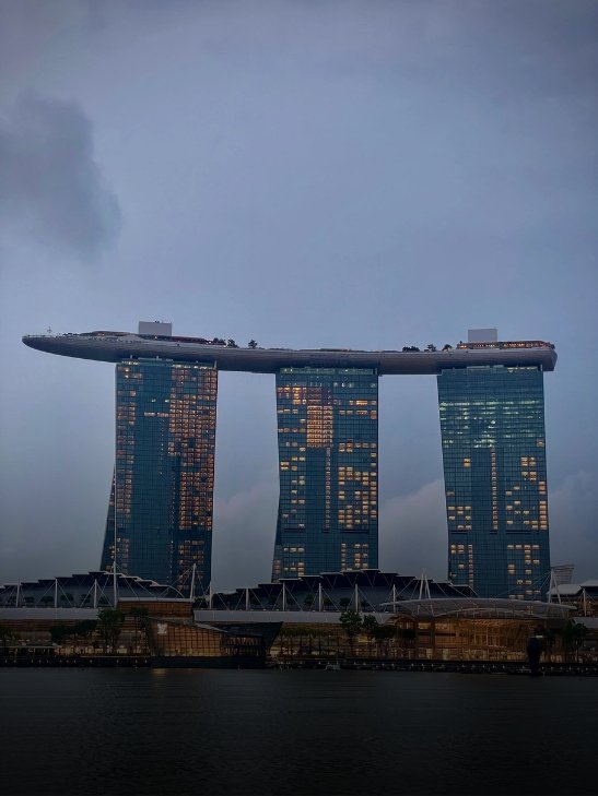 The iconic Marina Bay Sands hotel building against a cloudy evening sky in Singapore.