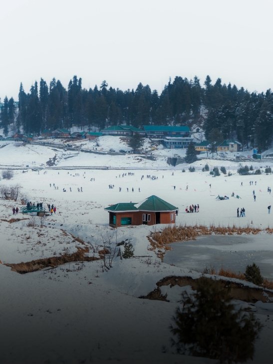 Tourists enjoying activities on a snow-covered valley landscape in Kashmir, India.